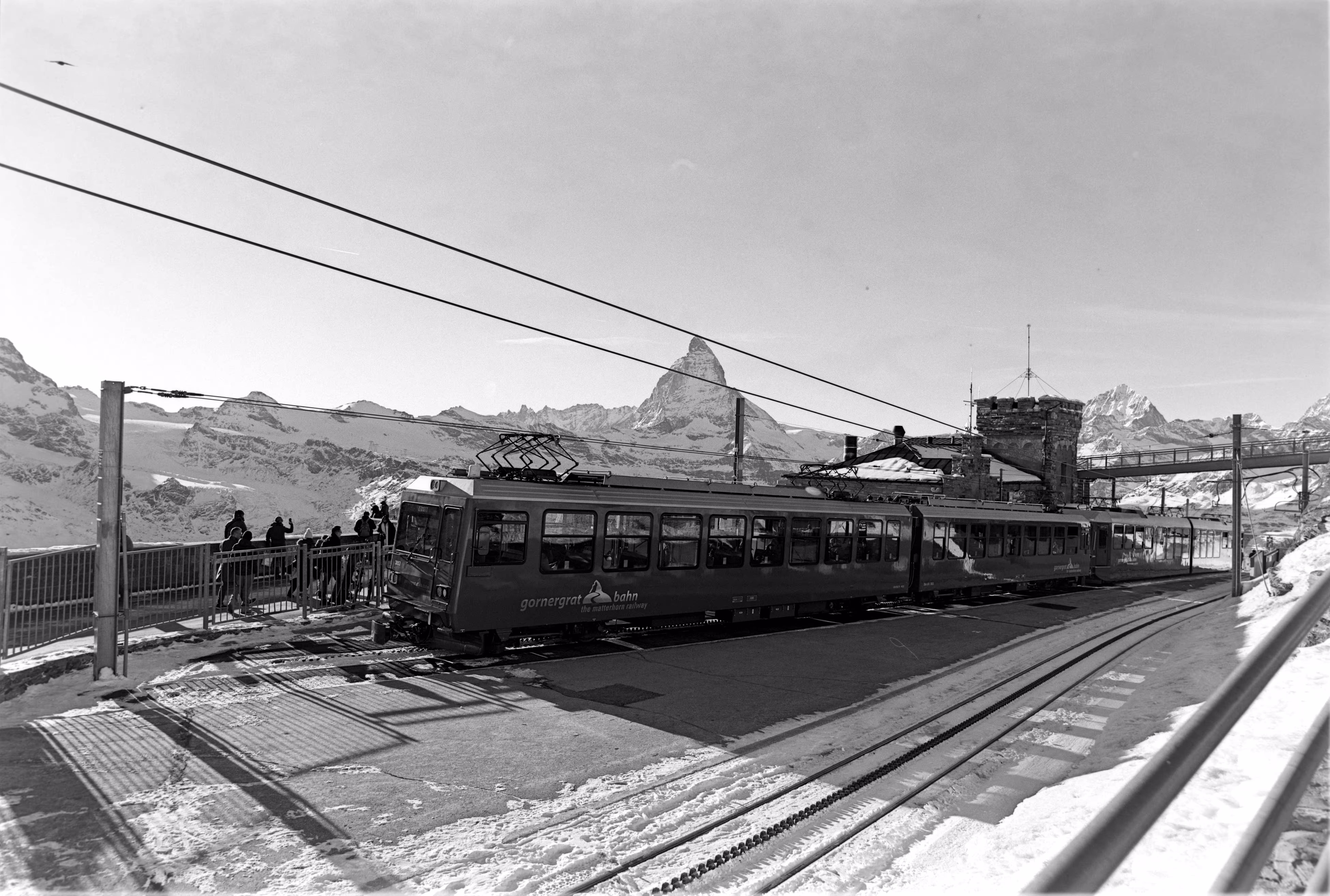 Cogwheel train traveling from Zermatt to Gornergrat in winter. Wide-angle black and white film photograph taken with a Zeiss Distagon 21mm at Gornergrat, Switzerland