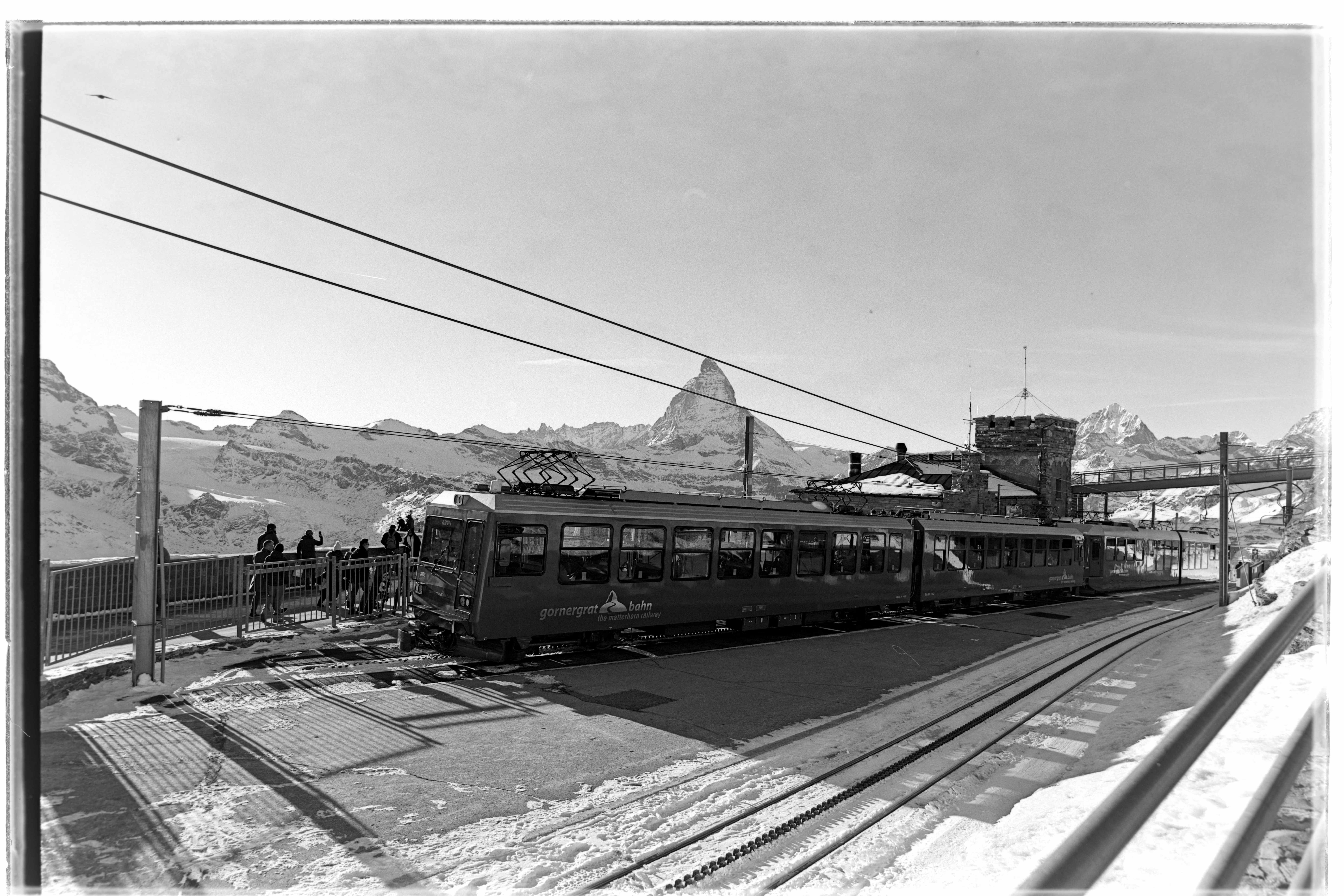 Cogwheel train traveling from Zermatt to Gornergrat in winter. Wide-angle black and white film photograph taken with a Zeiss Distagon 21mm at Gornergrat, Switzerland